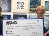 Arthead's Sonja Millis presents a $3320 cheque to Can Assist Southern Highlands President Jenny Harper, at the opening of the Blue Square Art Competition. Picture by John Swainston