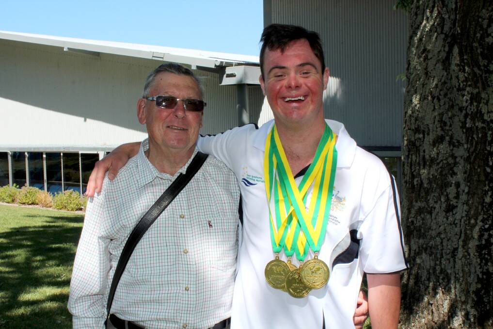 TOP EFFORT: Swimmer Daniel Rumsey with his father John. The athlete won five gold medals and two silver medals at the Down Syndrome National Swimming Championships.