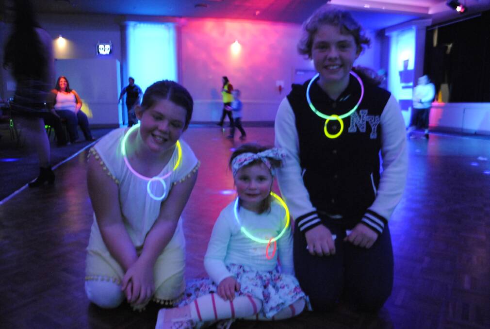 Jasmine (11), Matilda (3) and Maddy (12) loved the glow sticks at a Mittagong Blue Light Disco. Photo: Claire Fenwicke