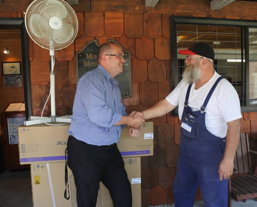 Harvey Norman Moss Vale's Lee Sanger-Young handing over the new air-conditioning unit to Moss Vale Men's Shed president Richard Milne, while the old fan waits for its new home. Photo: Claire Fenwicke