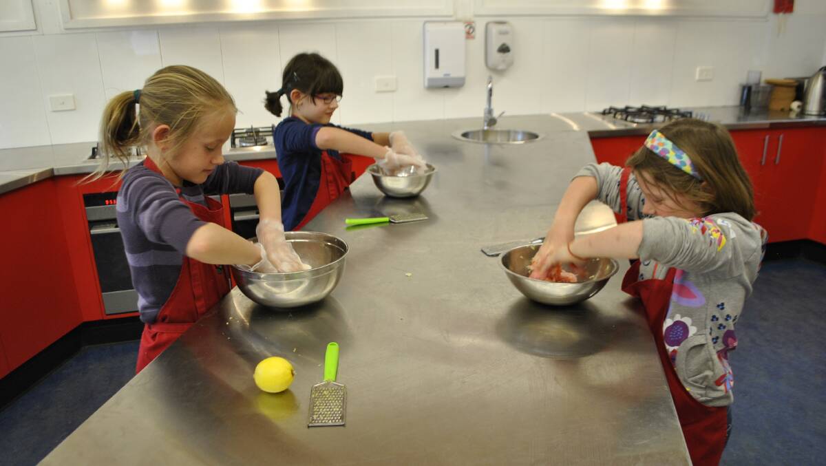 Ella (9), Rebekka (9) and Phoebe (7) used their hands to make Thai burgers during the winter school holiday cooking classes. Photo by Claire Fenwicke