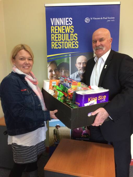 Southern Highlands Homelessness Services case worker Jodie Keeley accepting a food hamper donation from Highlands Business Circle member Gary Ponder. Photo: Claire Fenwicke