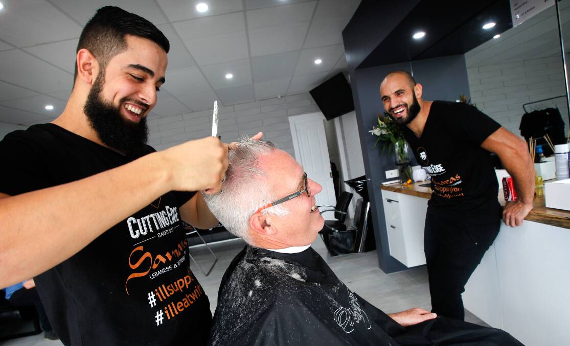 Graham Gould gets a haircut in a show of support for barber Bilal El Mohamad at a community event organised by Samara's restaurant owner and friend Omar Nemar (right) last month. Picture: Sylvia Liber