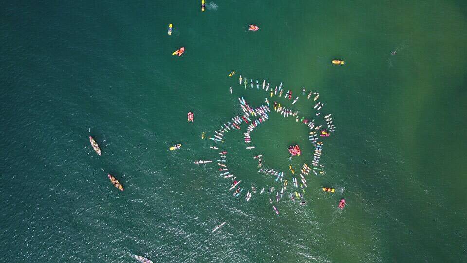 IN HONOUR: Board riders congregate off Thirroul Beach in a tribute to Dean Mercer, captured from the air.  