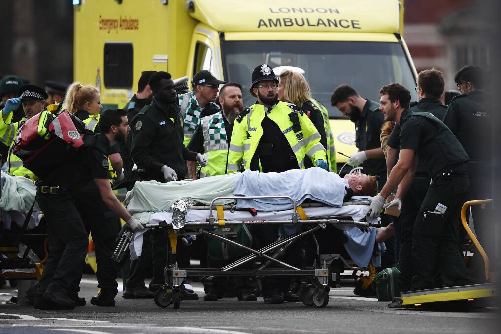 Casualties: A member of the public is treated by emergency services near Westminster Bridge and the Houses of Parliament. Picture: Carl Court