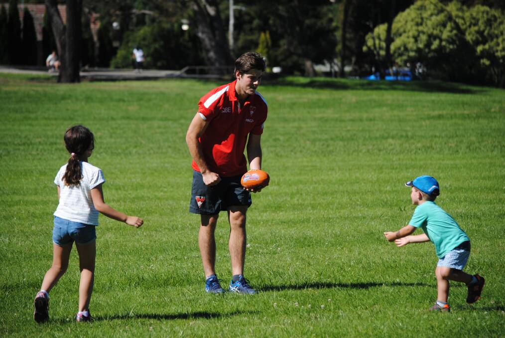 Sydney Swans player George Hewett handballs to a Highlands junior at Loseby Park. Photo by Josh Bartlett