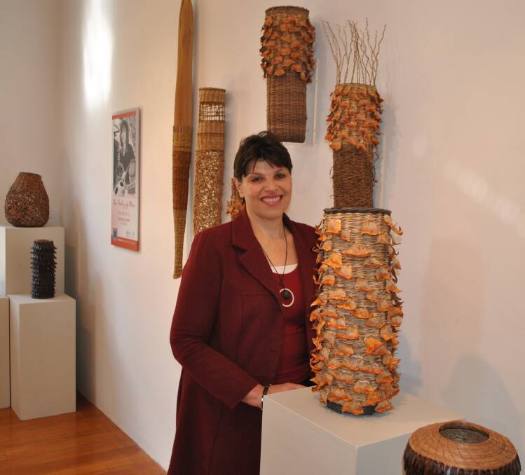 The Poetry of Place exhibition curator Slavica Zivkovic admires some of Virginia Kaiser's weaved baskets. Photo by Josh Bartlett