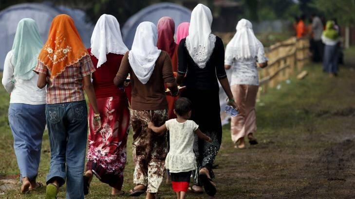 Rohingya migrants who arrived in Indonesia last week by boat walk back after collecting breakfast at a temporary shelter in Aceh Timur. Photo: Darren Whiteside
