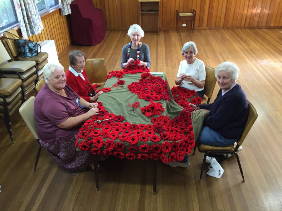 Country Women's Association members (L-R) Carol Nolan, Mary Orford, Rita Gilroy, Wendy Davis, and Beverley Worner stitching 800 crocheted and knitted poppies onto a cover for the Mittagong Cenotaph. Picture: Ainsleigh Sheridan