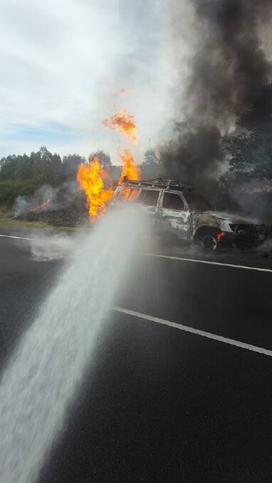 Fire fighters worked together to extinguish a car on fire on the Hume Highway at Sutton Forest on Sunday. Photo: Berrima Rural Fire Brigade