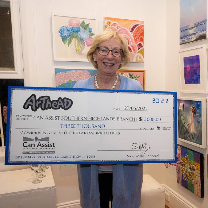 Can Assist Southern Highlands President Jenny Harper holds the $3000 check that has been raised for the charity so far through ArtHead's Blue Square Art exhinition. Picture: Supplied
