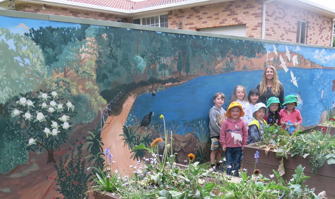 Sarah Hillsley stands in front of the Mittagong Preschool mural with her children and other kids from the preschool. Photo: Sarah Hillsley