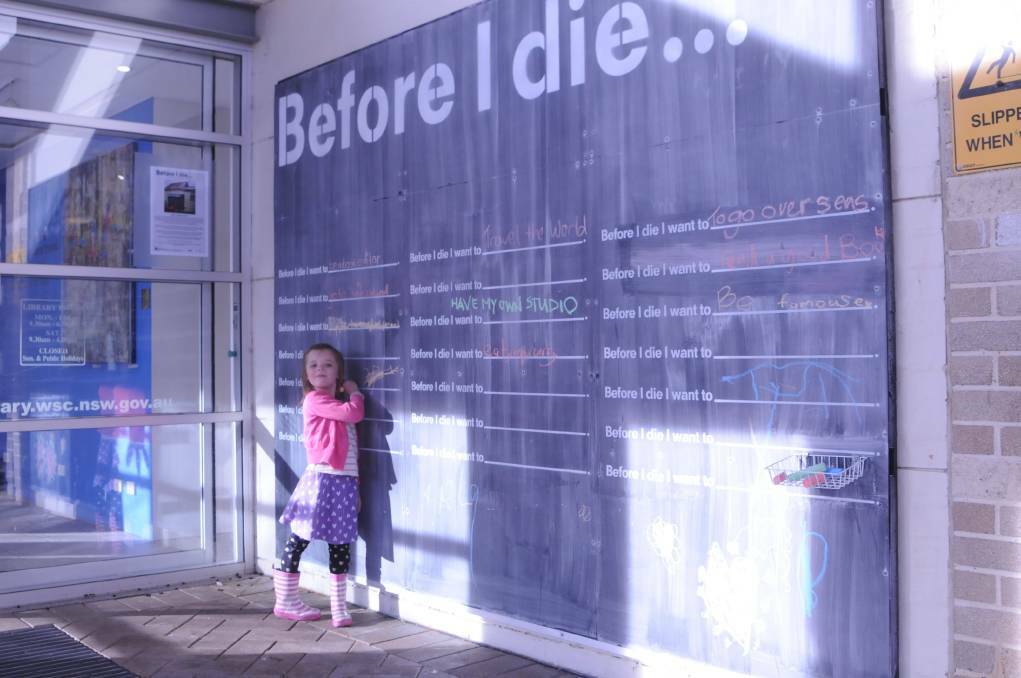 Imogen Raschke writes on the Before I Die wall outside Bowral Library. Picture: Lauren Strode
