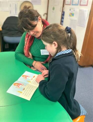 Kathleen sits with a student at Moss Vale Public School. Picture: Supplied 