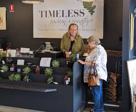A Timeless shop volunteer helps a customer in Bowral. Picture supplied.