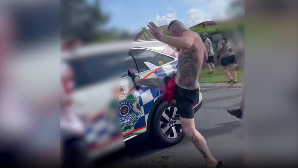 A man kicks the door of a police car in Logan on March 9. Picture supplied by Queensland Police