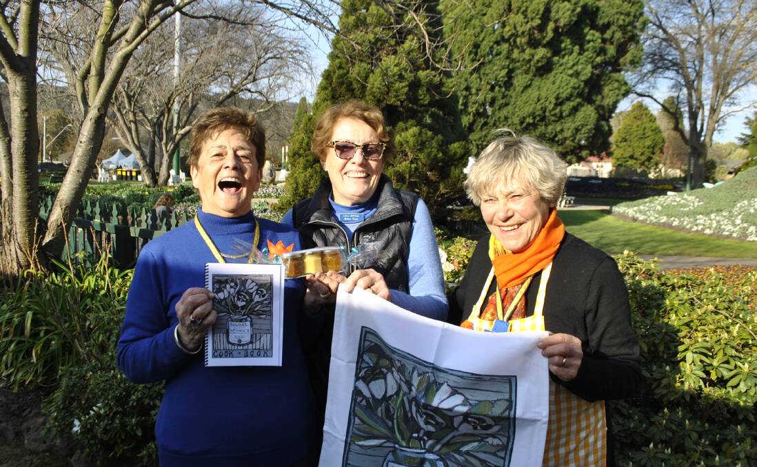 Bowral CWA secretary Diana Innes, vice president Helen Kent and publicity officer Maggie Stewart pose with the group's new cookbook and tea towel. Photo: Charli Shield. 