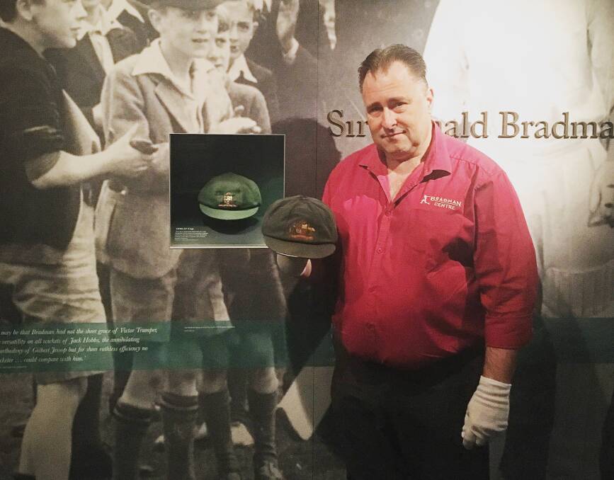 Bradman Museum's curator Andrew Summerell holding Justin Langer's original Test cap next to the great Sir Donald Bradman's baggy green. 