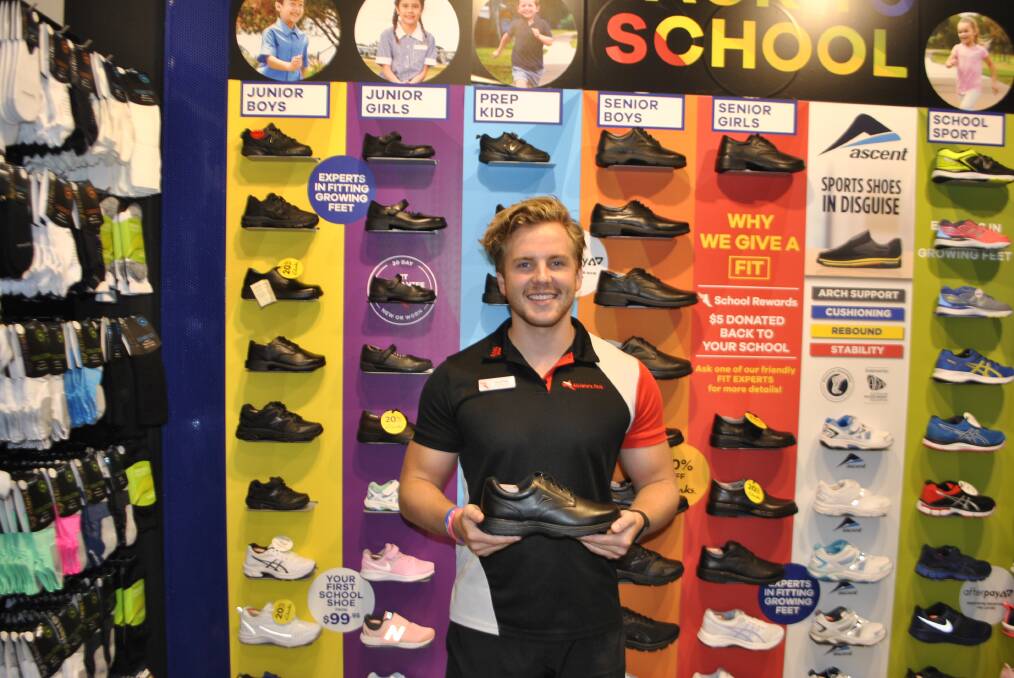 Matthew from the Athlete's Foot, Bowral showing off the back to school wall range available. 