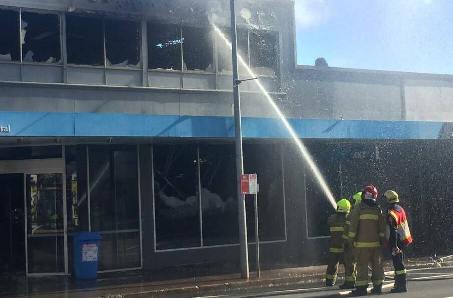 Firefighters attempting to cool hot spots in the roof of the ANZ Bank following last week's blaze. Photo: Michelle Haines Thomas