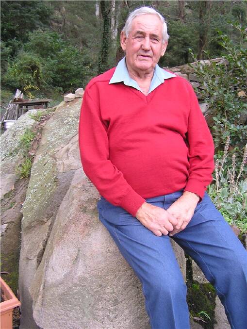 TRACHYTE REMAINS: Fourth generation quarryman and stonemason Bill Pope is pictured in 2009 sitting on a Bowral trachyte found in his backyard. He is sure there is still plenty of trachyte left in Mount Gibraltar.