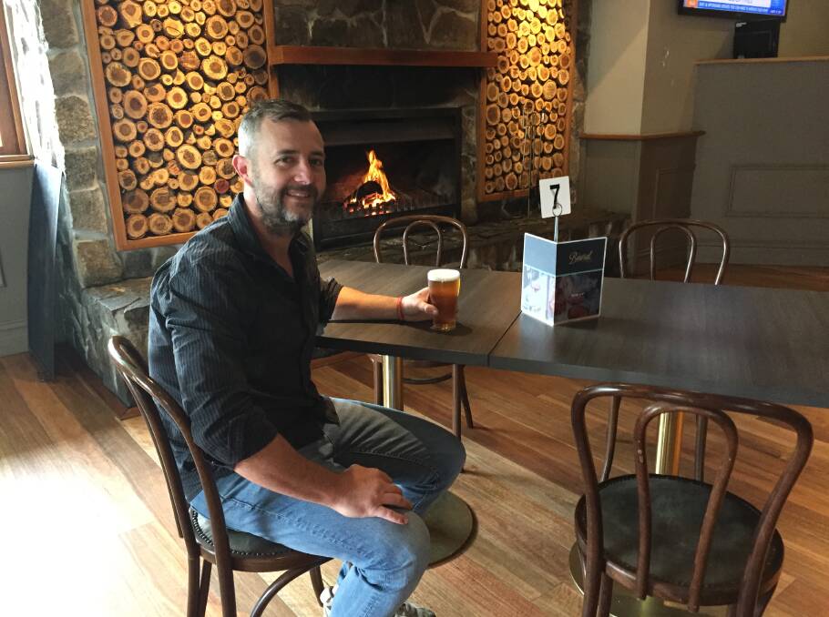 Publican Conor Murray enjoys a beer by the fire at Bowral Hotel.