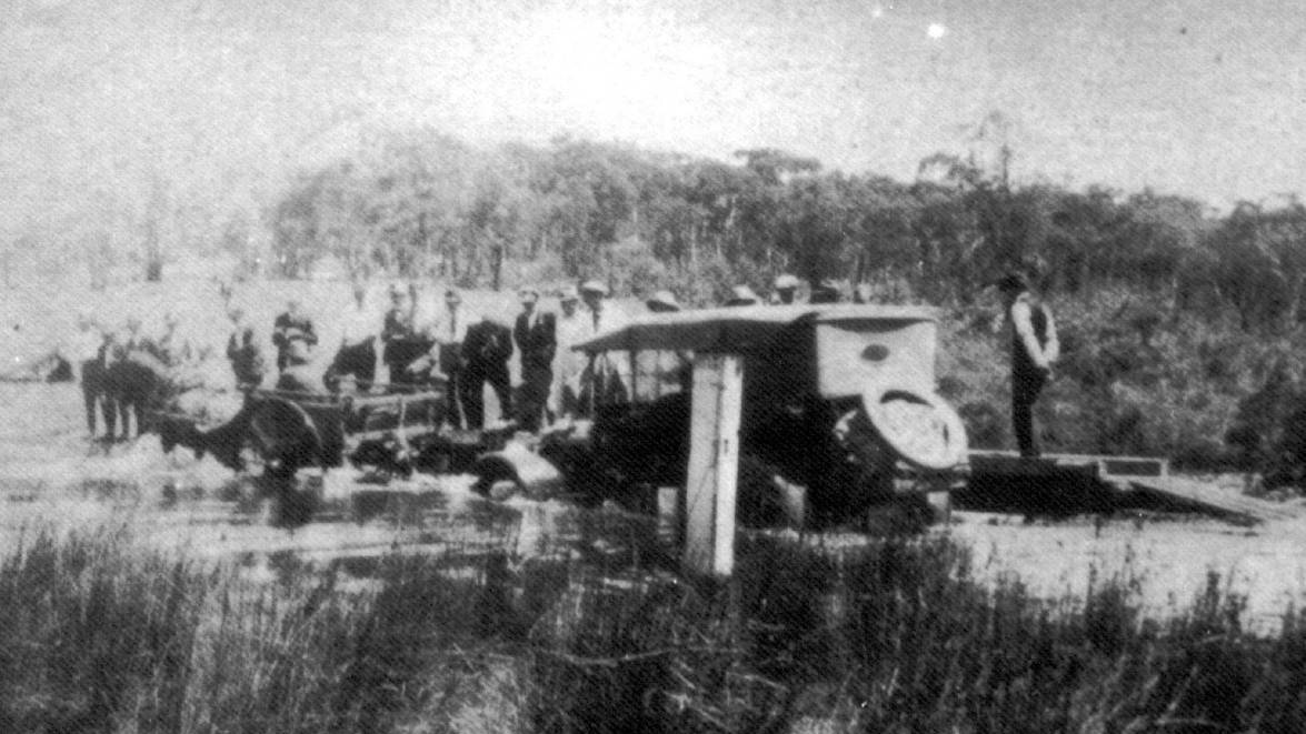 HORSE POWER: Motor car towed by dray across the flooded Paddy s River bridge in 1914.