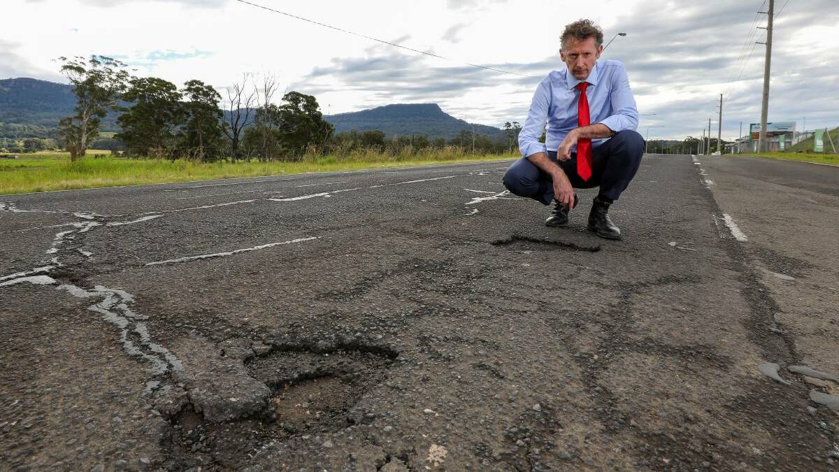 Holes: Whitlam MP Stephen Jones inspects some potholes. He said a Labor government would provide millions of dollars to repair roads nationwide. Picture: Adam McLean