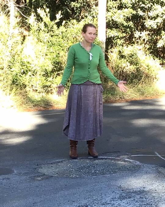 Bundanoon resident Rachel Russell stands infront of a large pothole. Photo: Supplied.