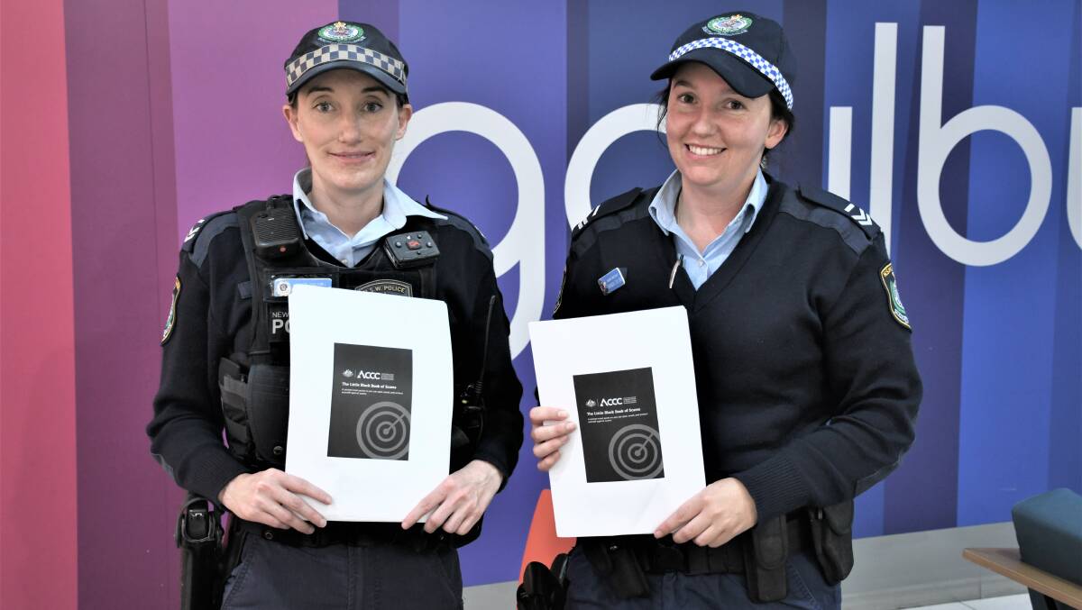 SCAM WATCH: Senior Constable Belinda McDonald and Senior Constable Amanda Collins with the Little Black Book of Scams. Photo: Hannah Neale