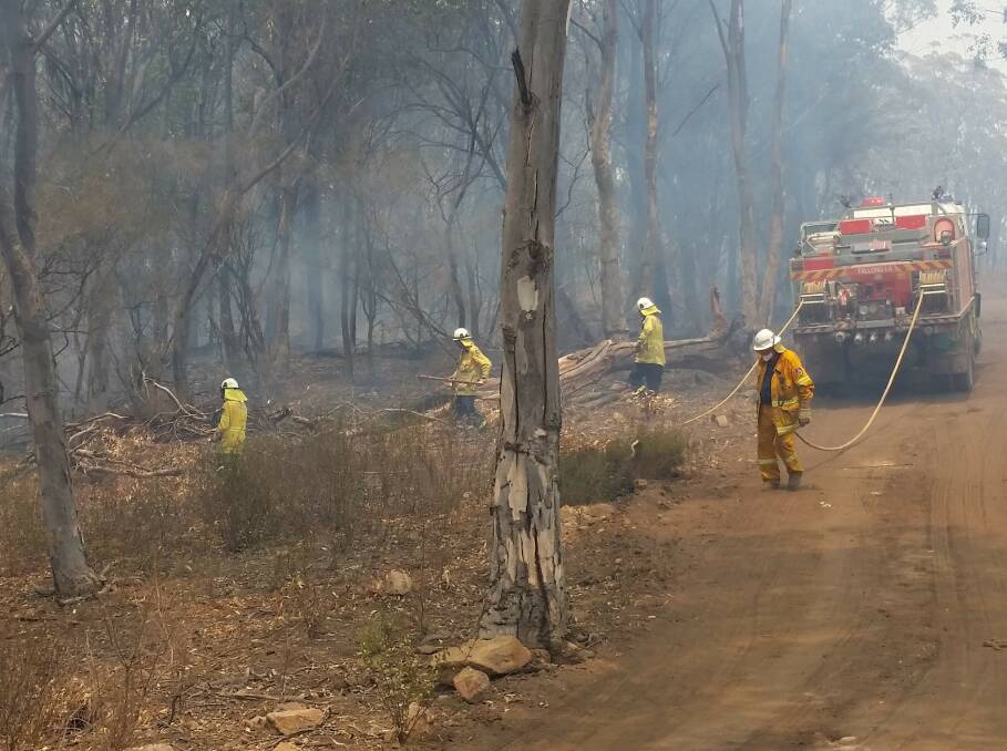 Tallong Rural Fire Brigade members working along Caoura Road on Tuesday afternoon after the Currowan fire spotted over the Shoalhaven into Bungonia Gorge. Photo supplied.