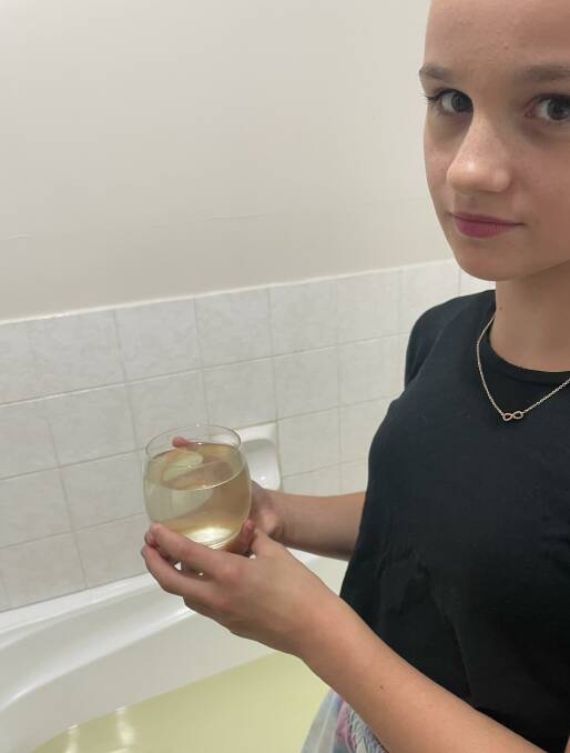 WATER WORRIES: Kelly Vinken's daughter, 12-year-old Abigail Abrahams, demonstrates discolouration to Marulan's drinking water. Her mother says it is unfit for drinking, bathing and showering. Photo supplied.