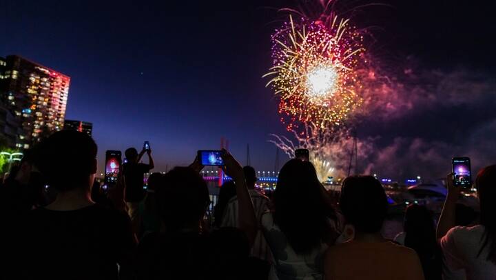 Revellers film fireworks over a night time city skyline. Picture from Shutterstock