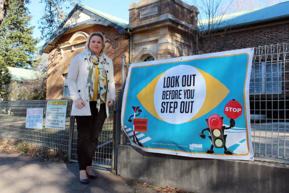 Road safety officer Melanie Lausz with the custom Look out before you step out banner at Bowral Public School.