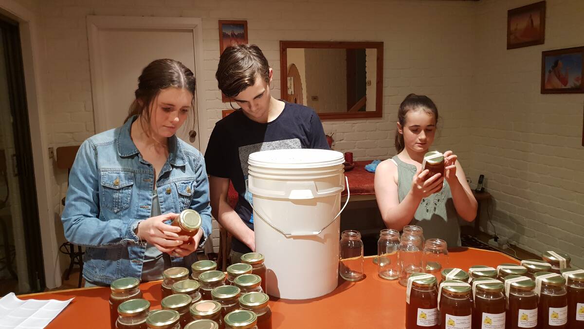 Amy, Luke and Claire McClay of Bowral decanting and labelling pure honey donated from their father's business, Southern Honey for the food drive. Photo: supplied.