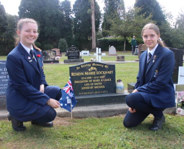 Students place Australian flags on gravesites and memorial plaques. 