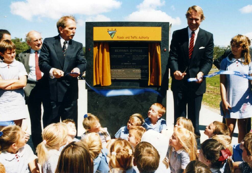 JOYFUL DAY: Cutting the ribbon to open the Berrima Bypass in 1989 are Bob Brown, Federal Minister for Land Transport (left) and Bruce Baird, NSW Minister for Transport, with local school pupils in attendance. Photo: BDH&FHS.