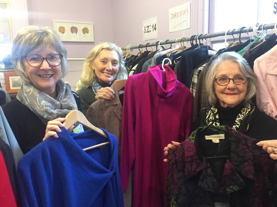 RUG UP: Youth Off the Streets op shop volunteer staff Lois, Susie and Mary with some of the winter stock now available.