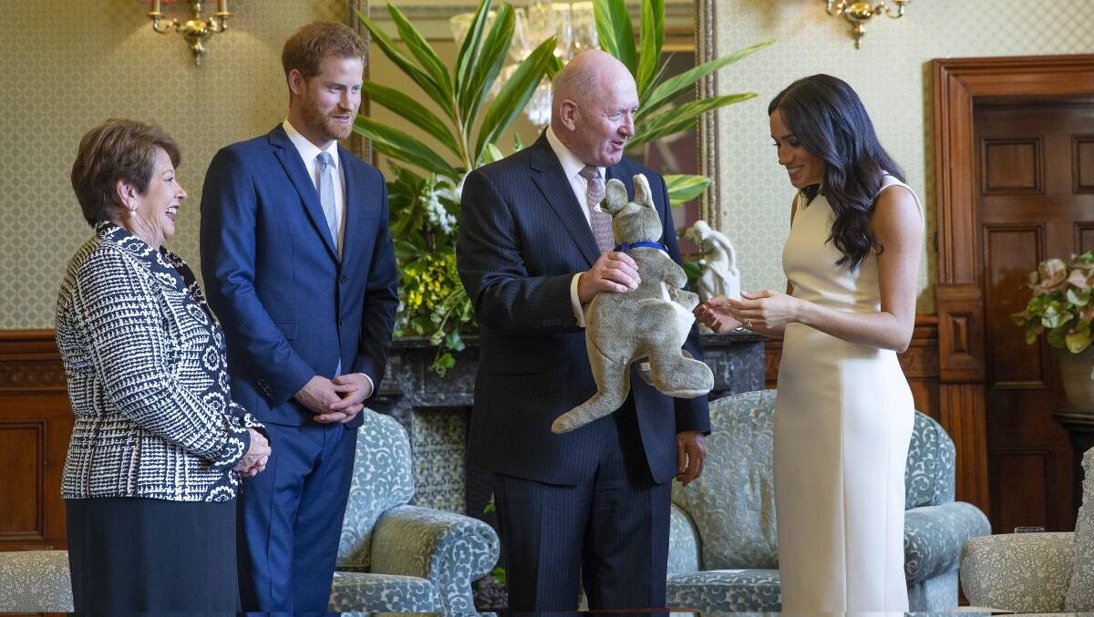Australian Governor-General Sir Peter Cosgrove and his wife Lady Cosgrove present a toy kangaroo to Prince Harry and Meghan Markle during an event at Admiralty House in Sydney. Photo: AP
