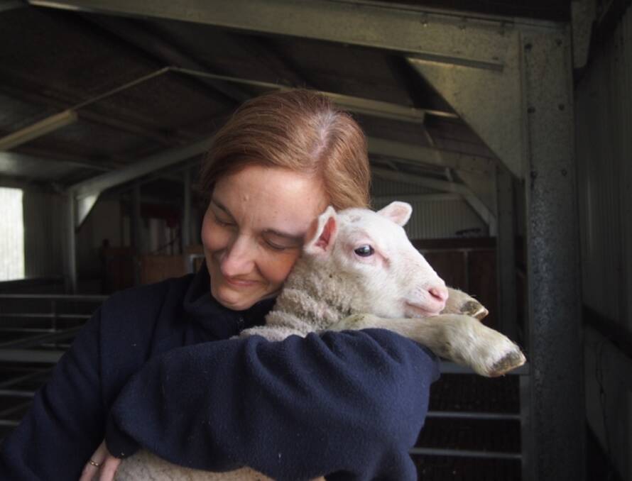 Cressida McNamara cuddles one of their lambs. Photo supplied
