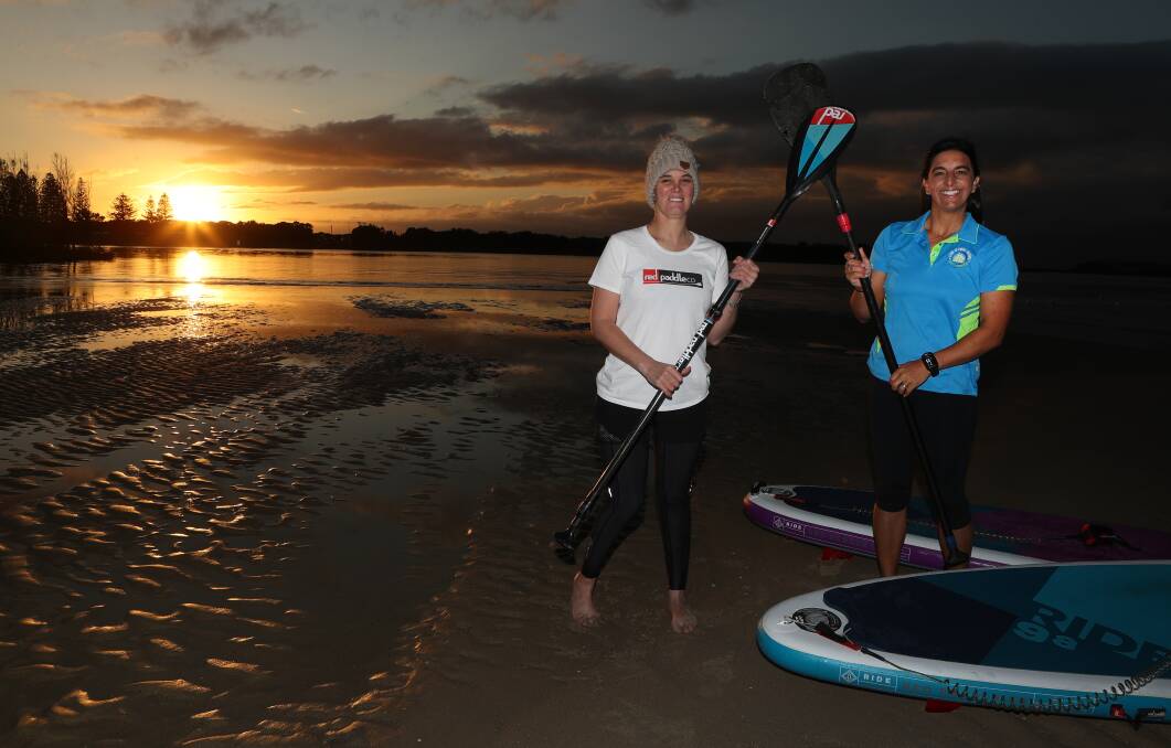 Shining tourism star: Stand Up Paddle Boarding Shellharbour's Rebecca Dunning (right) gives Sara Egan a a lesson at Reddall Reserve, Lake Illawarra. Picture: Robert Peet.